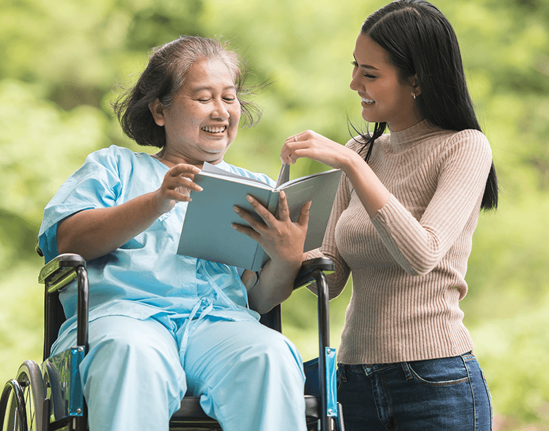 Professional Caregiver Assisting Senior Citizen in a Wheelchair Out in Nature